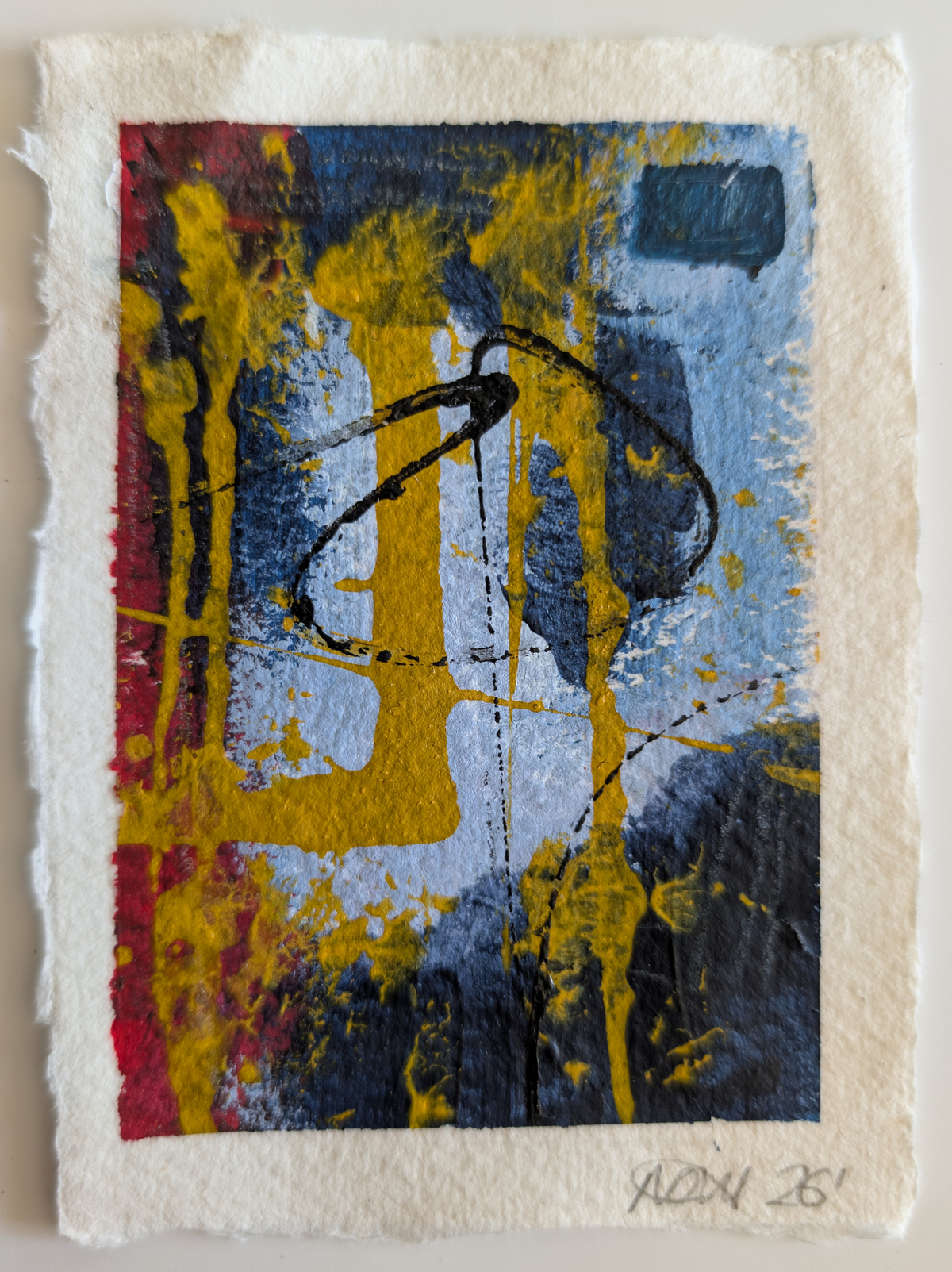 An abstract art print on textured handmade paper, featuring a colorful composition of yellow, blue, red, and black paint with a white border, signed 'NJG 26' in the bottom right corner.
